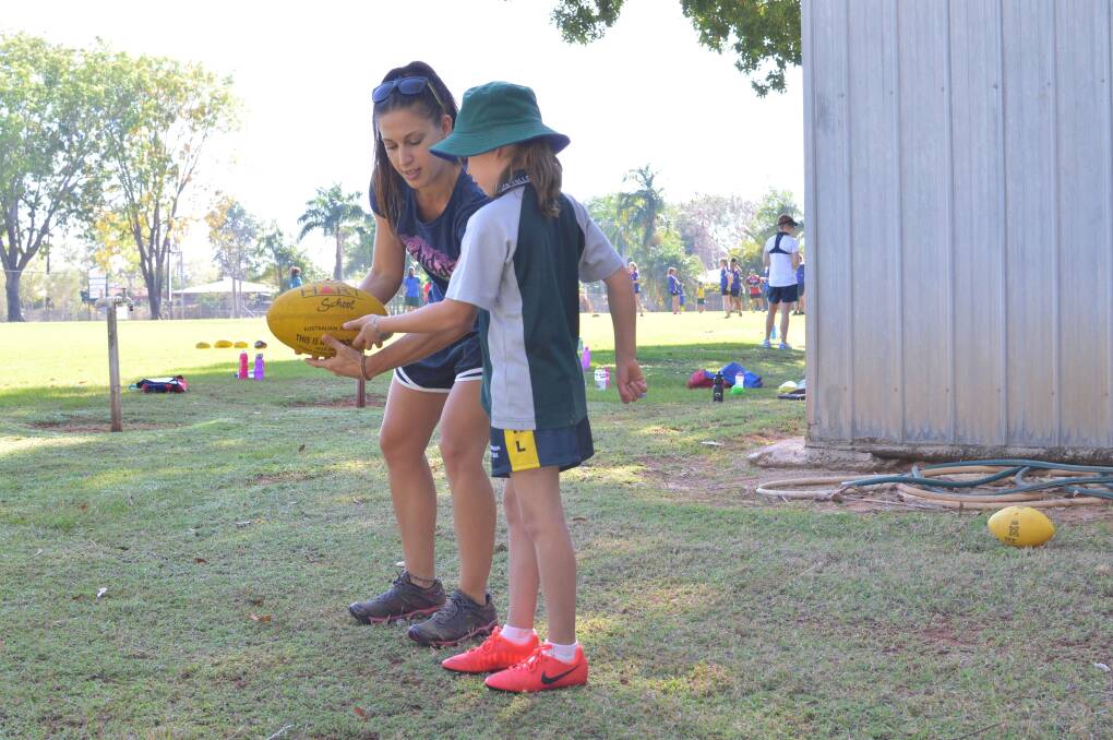 LEADING THE WAY: Newly-crowned AFLNT School Ambassador of the Year Elyse Borlini shows Year 3 student Maddy Edmonds the finer points of handballing during a Future Leaders Football School skills session on Friday.