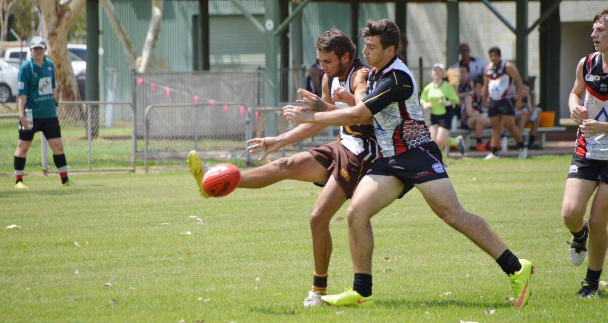 CROC ATTACK: Steven Mole gets a late kick away for the Big River Hawks before he is hammered by a Southern Districts Crocs defender at Nitmiluk Oval on Sunday afternoon.