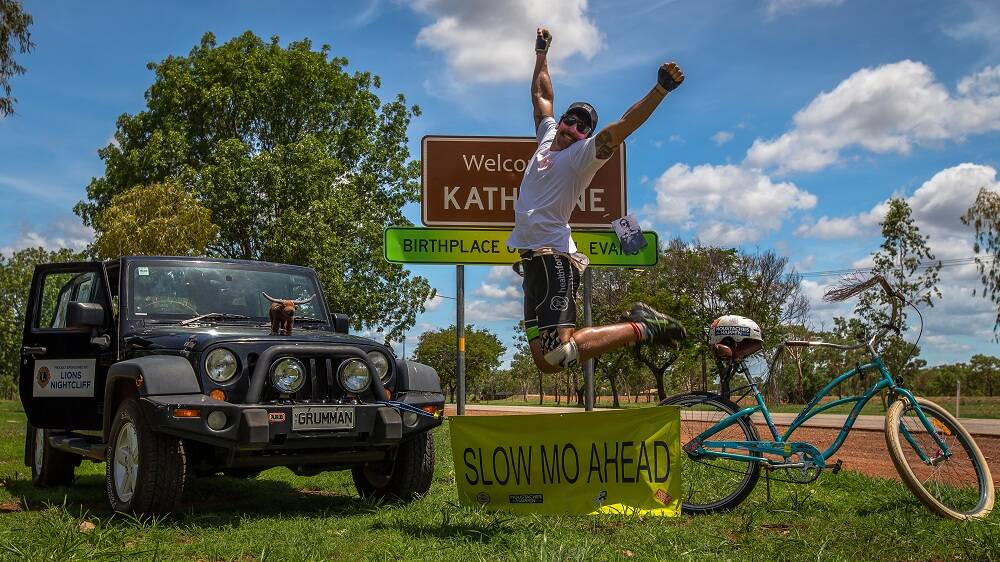 WHAT A FEELING: A jubilant Dan Mewing kicks up his heels after arriving in Katherine on his wife’s bicycle as part of this mammoth Movember fundraising effort earlier this month.