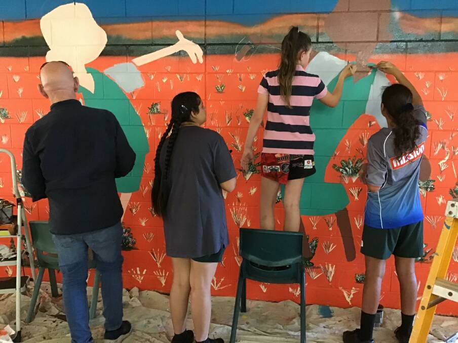 HARD AT WORK: Cartoonist Jeff Taylor was given a hand by students when painting the mural. Picture: Ginny Edwards.