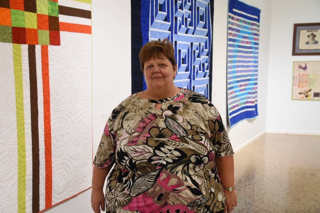 Sharron Buzzo with her three large artworks in the background. 