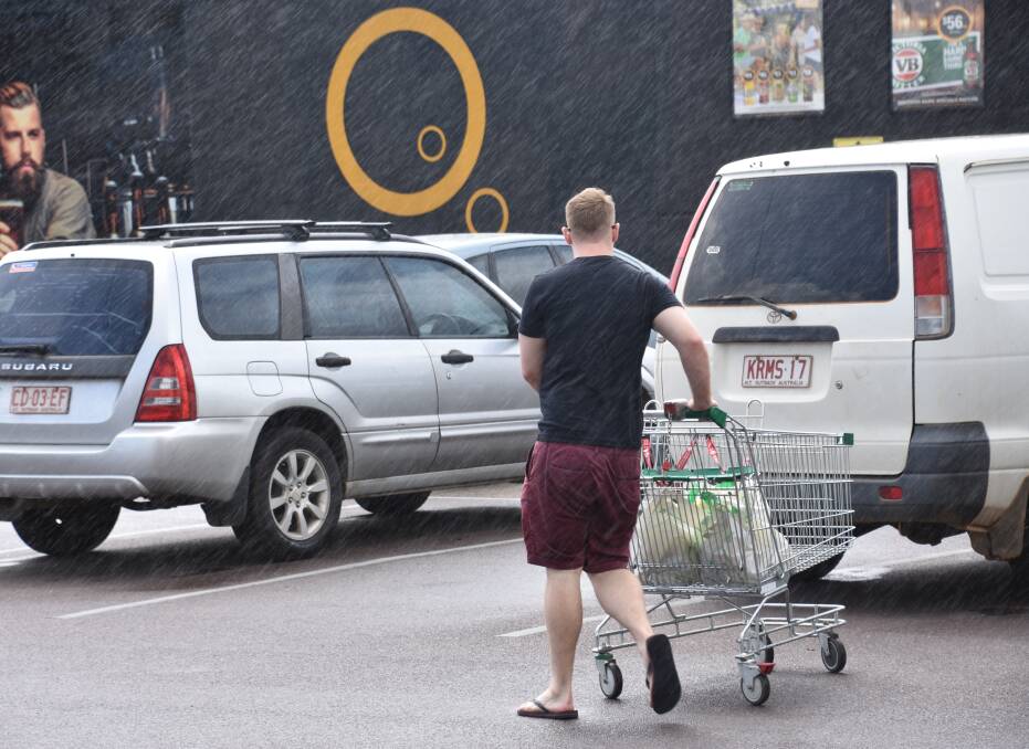 A shopper is caught in the first real monsoonal rains of the wet season. 