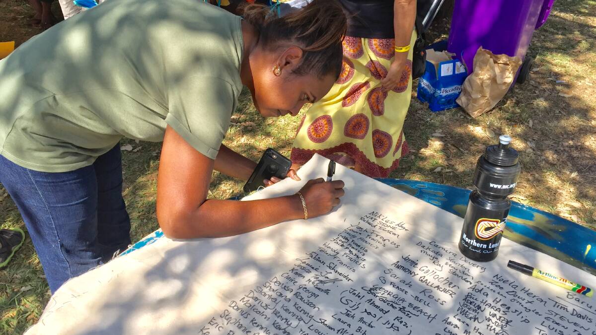 Kitty Storer from the Daly Region adds her signature to the thousands calling for a change, at Barunga Festival. 