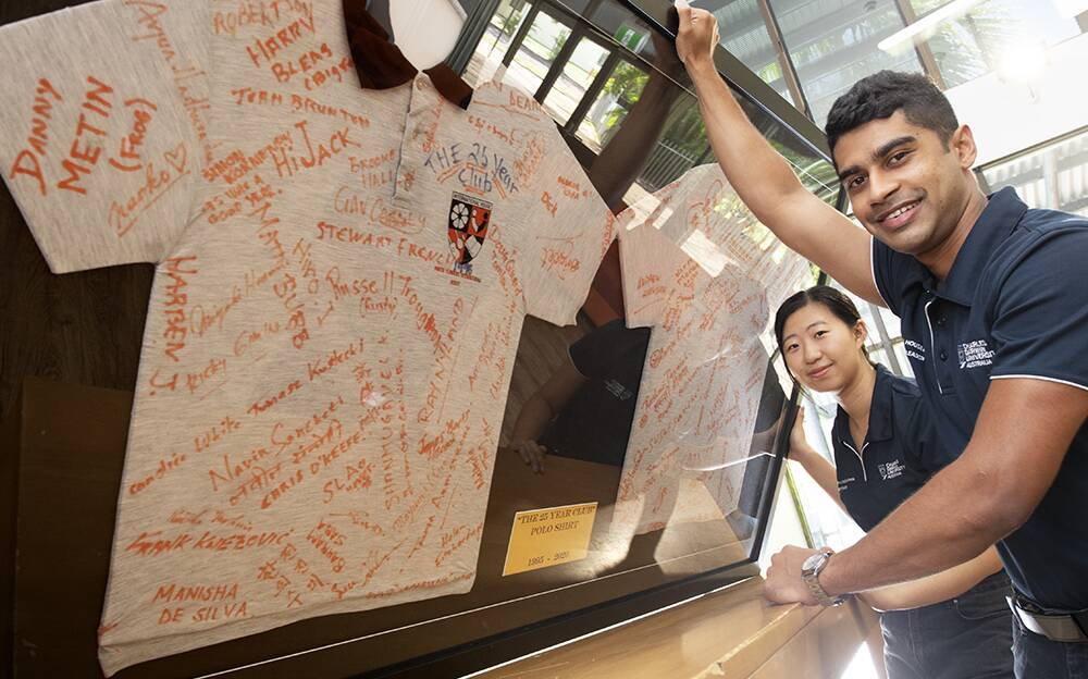IHD students Huiting Shen and Samith Franda with the signed shirt retrieved from a time capsule which had sprung a leak.