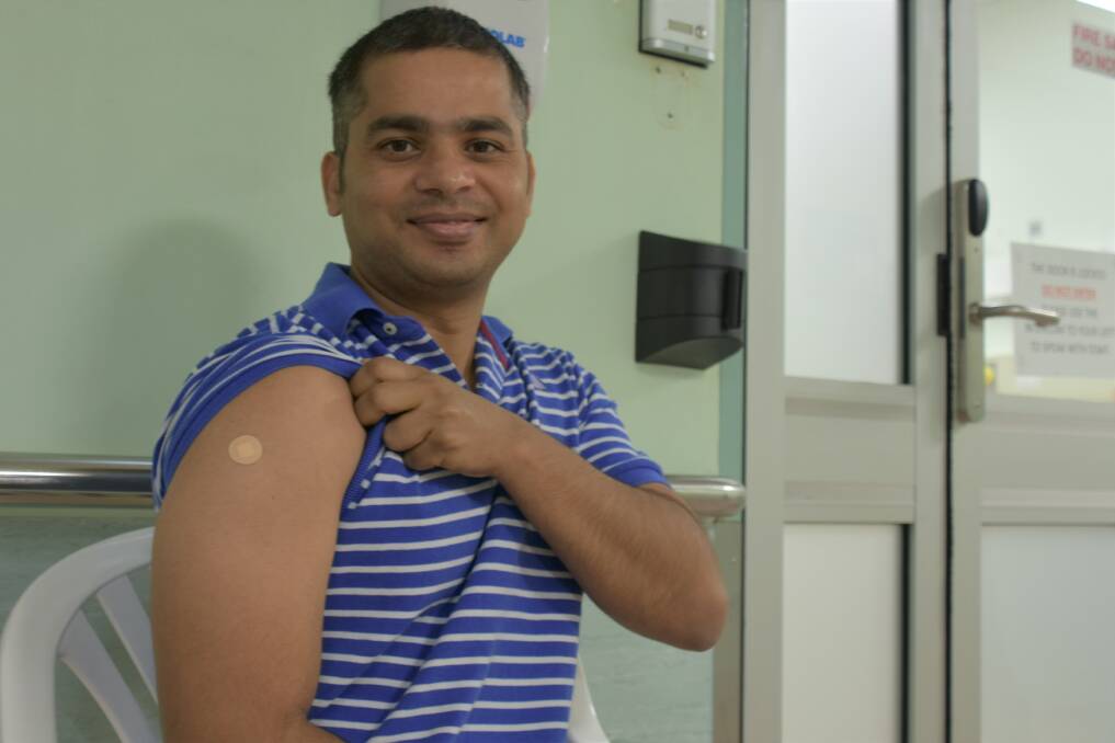 Bikalpa Gautam shows where he received the vaccine. Photo: Tom Robinson. 