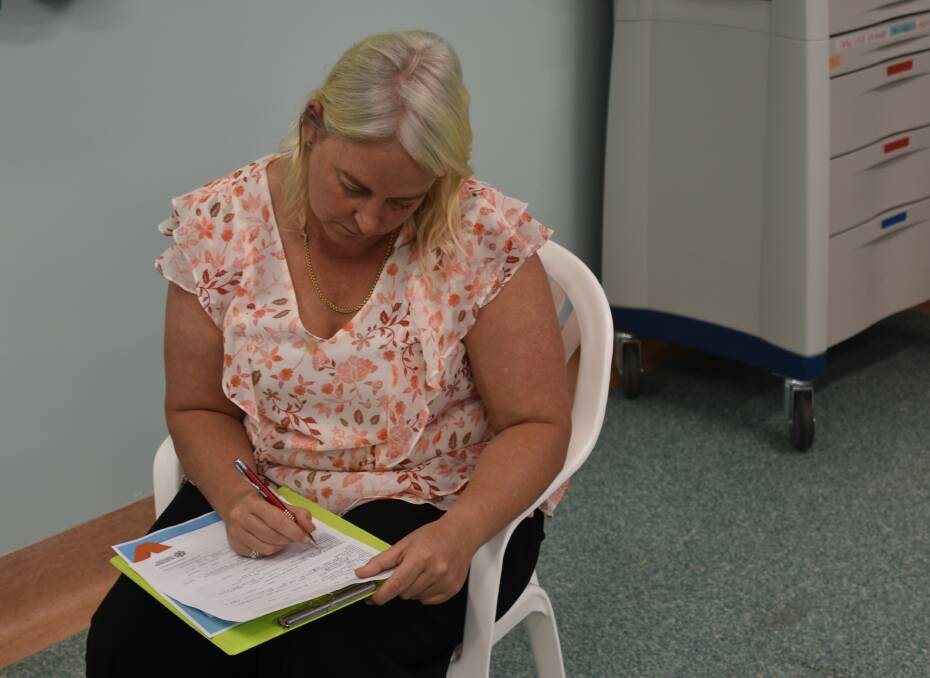 Mel Goss completes her paperwork before getting the vaccine. Photo: Tom Robinson. 