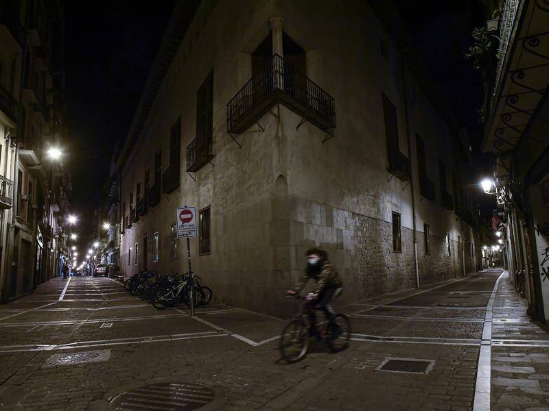 A masked cyclist crosses an empty street in Pamplona as Spain's new measures against COVID-19 begin.